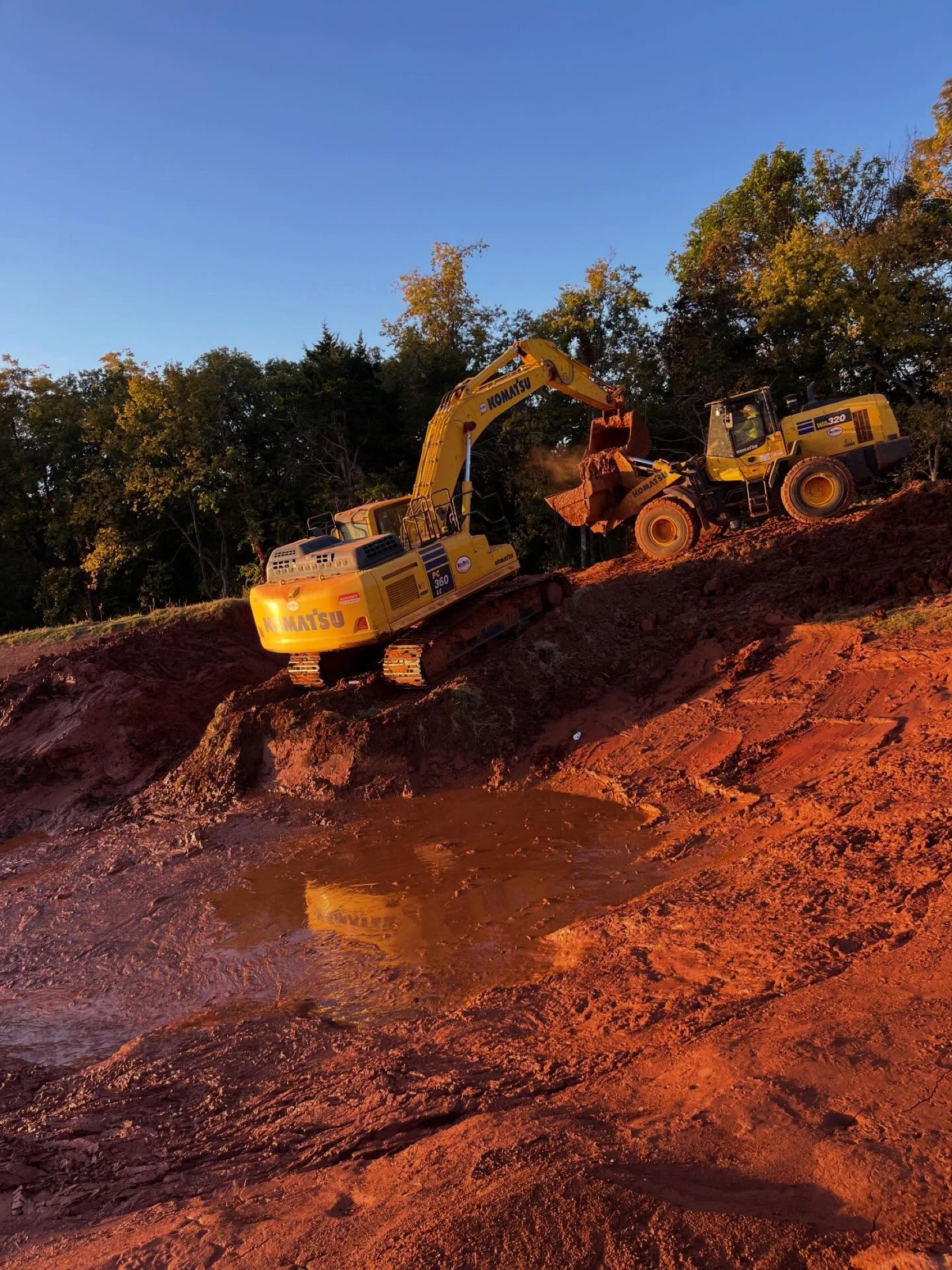 Excavator loading a haul truck at sunset on a First Water site