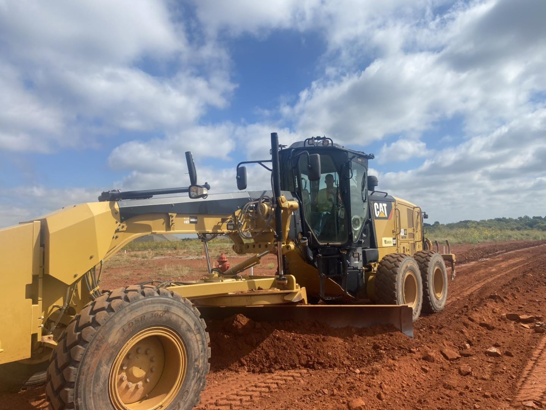 Motor grader cutting grade on a raw Oklahoma jobsite