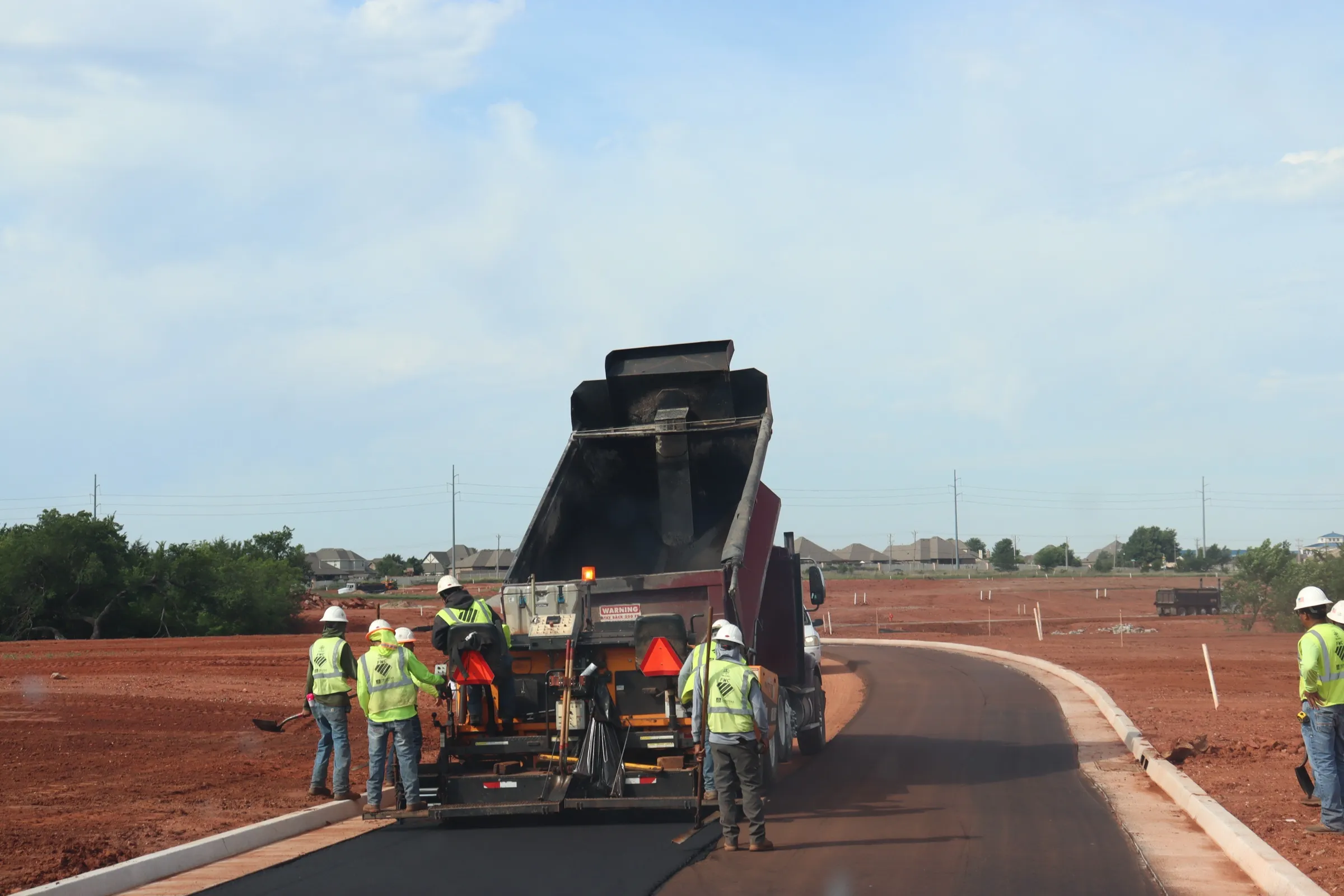First Water paving crew placing asphalt on a new street
